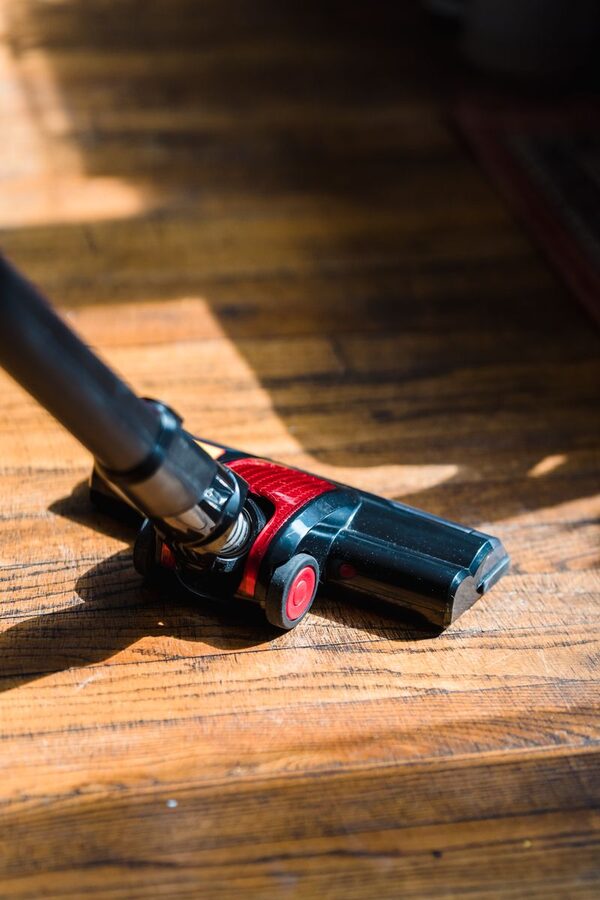 Vacuum cleaner working across a sunlit hardwood floor